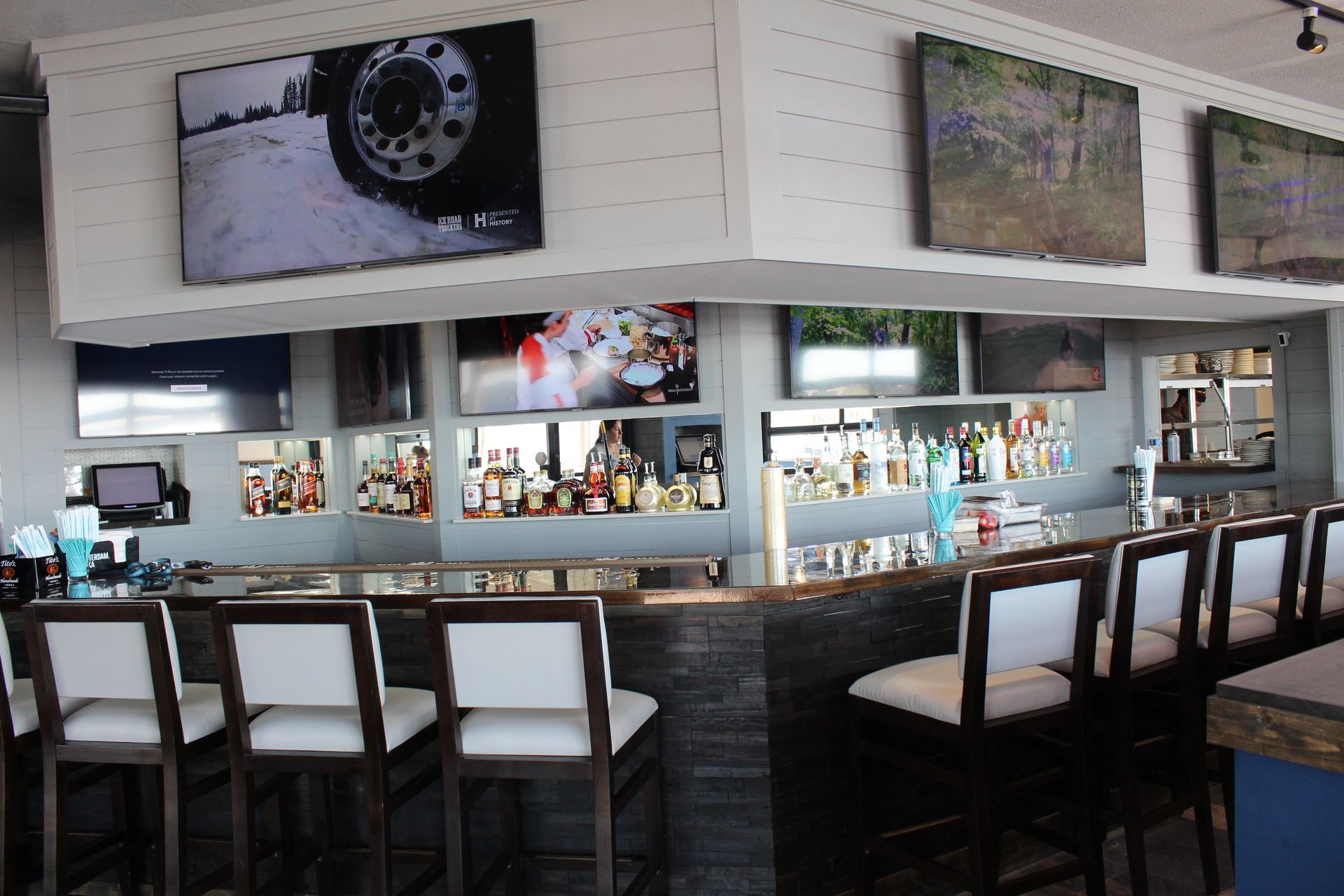 A bar with a lot of chairs and bottles on it