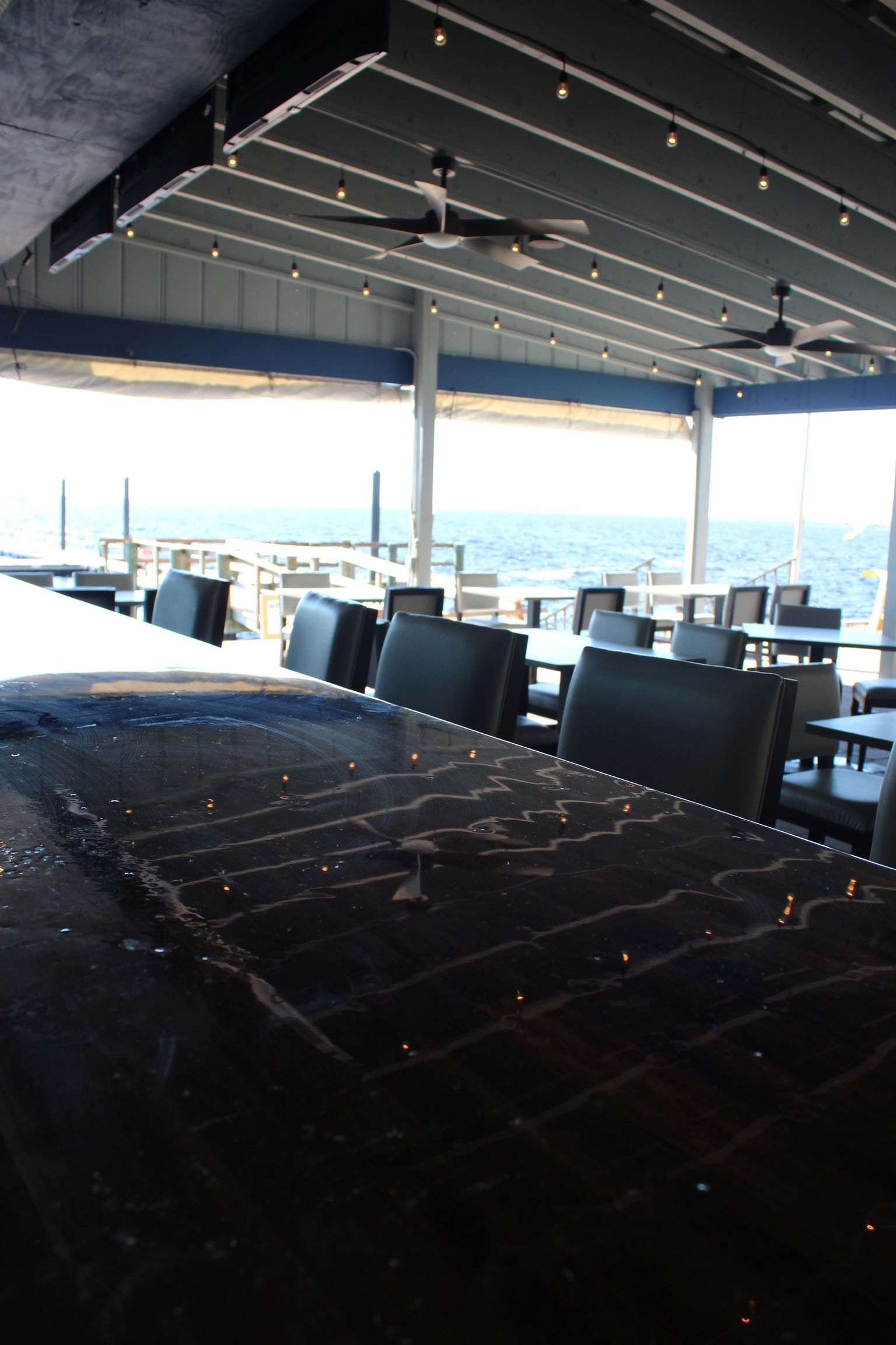A restaurant with tables and chairs overlooking the ocean