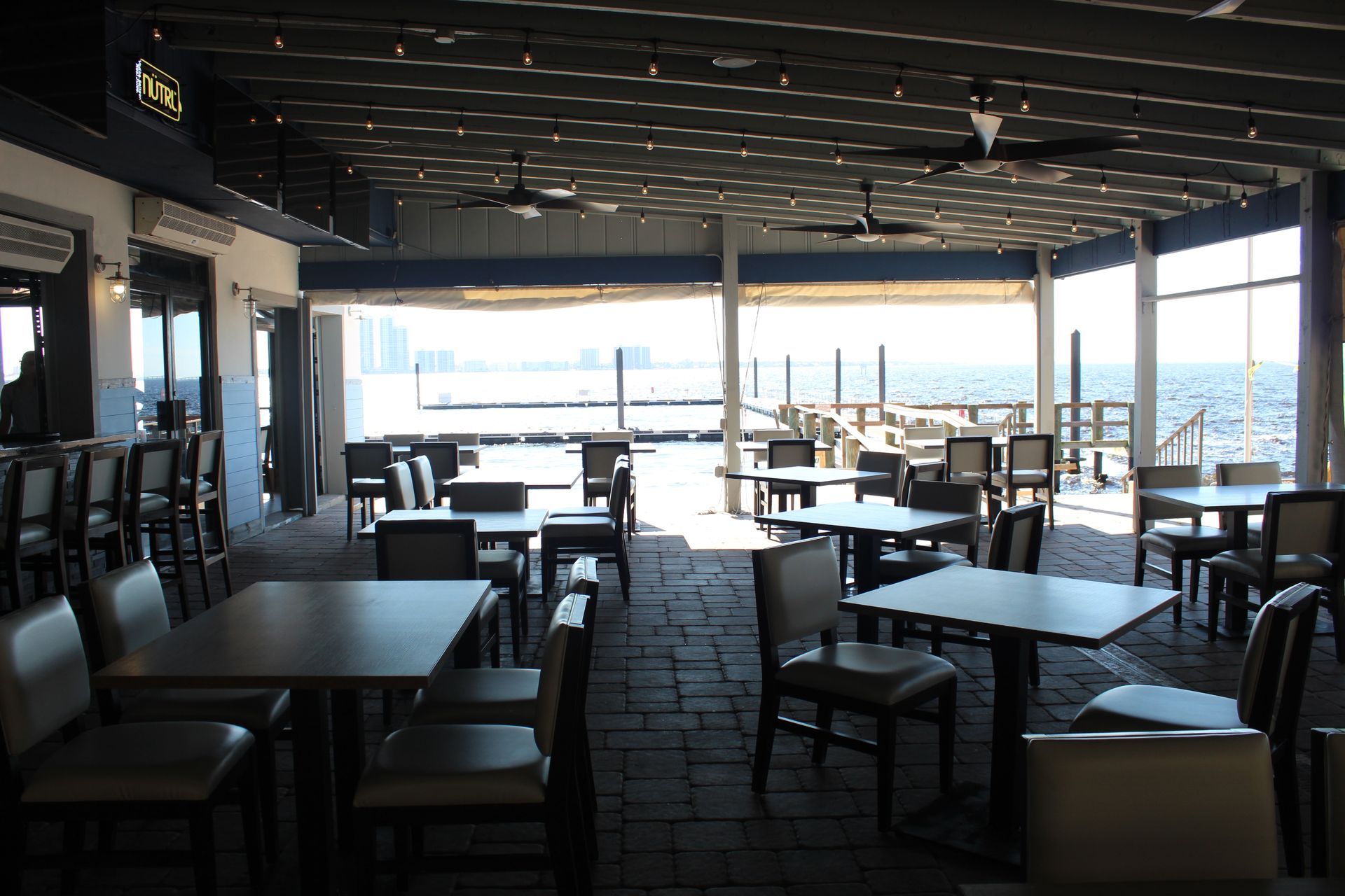 A restaurant with tables and chairs and a view of the ocean