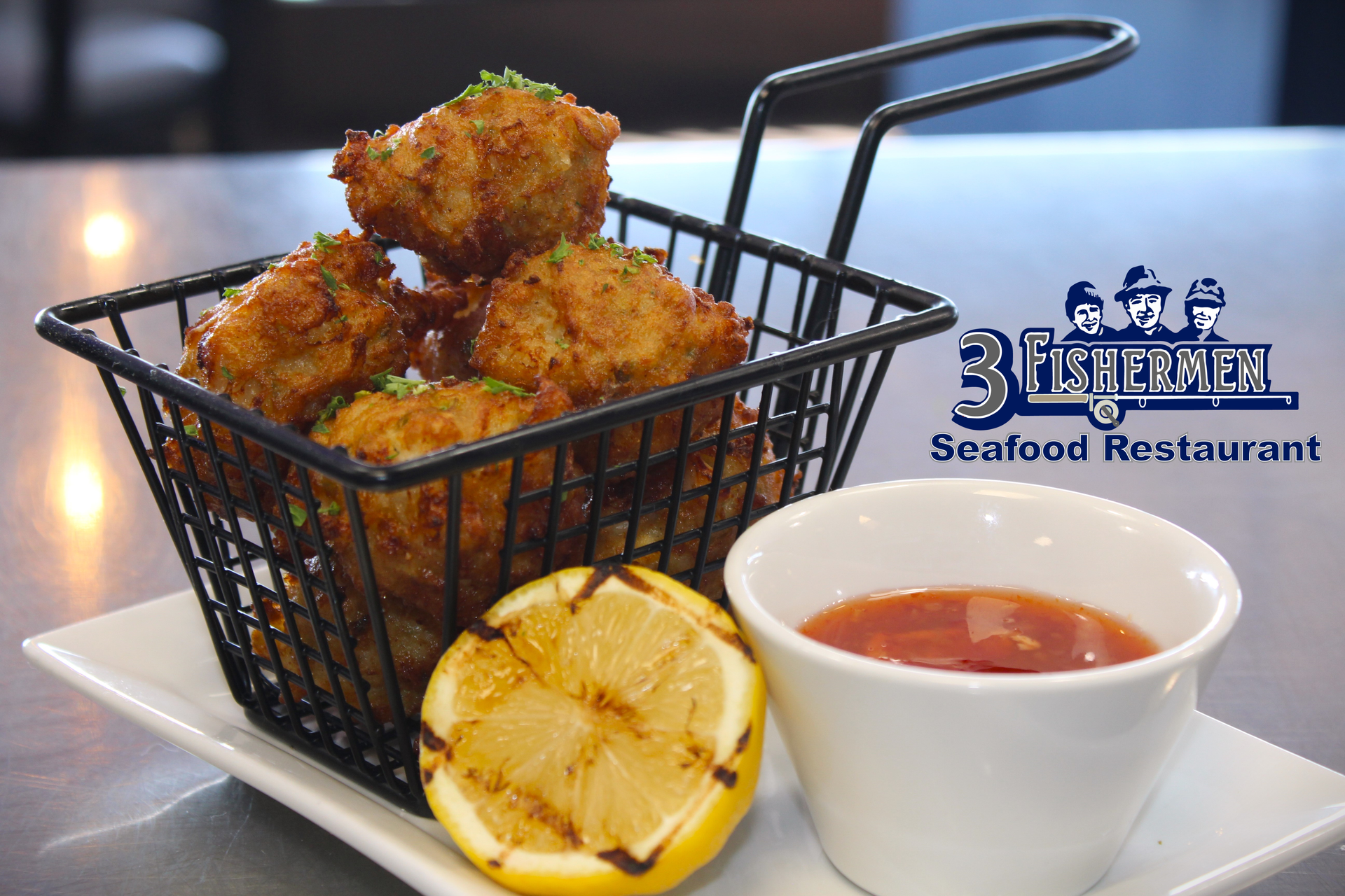 A basket of food is on a plate next to a bowl of sauce.