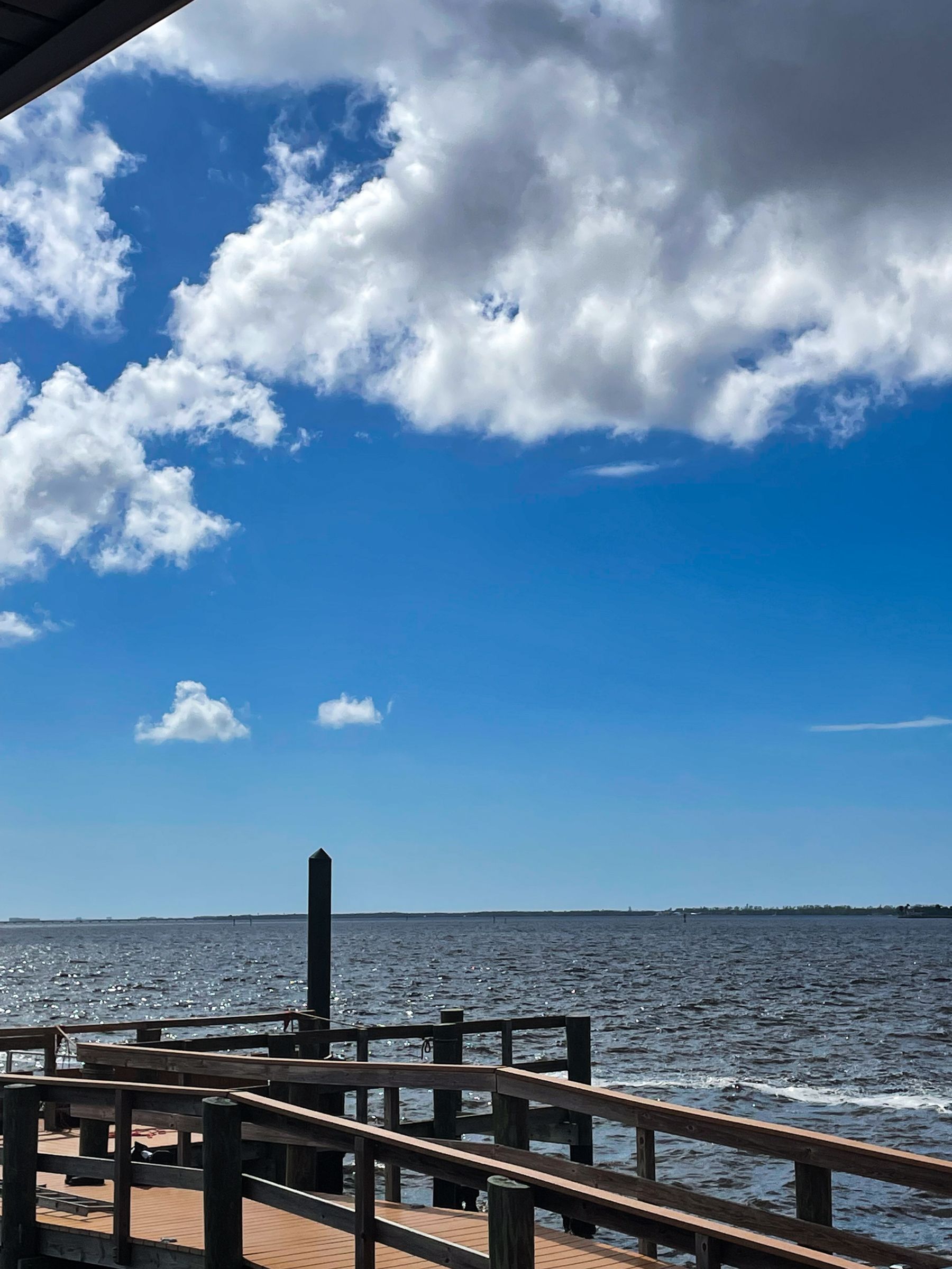A dock overlooking a body of water with a blue sky and clouds