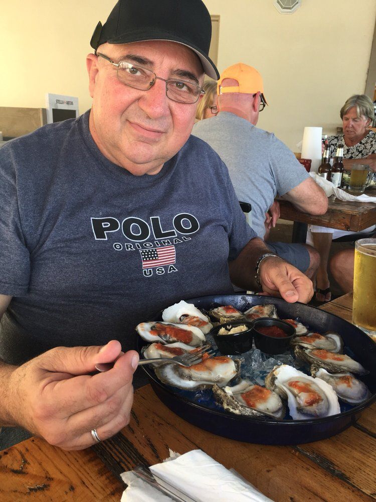 A man wearing a polo shirt is eating oysters