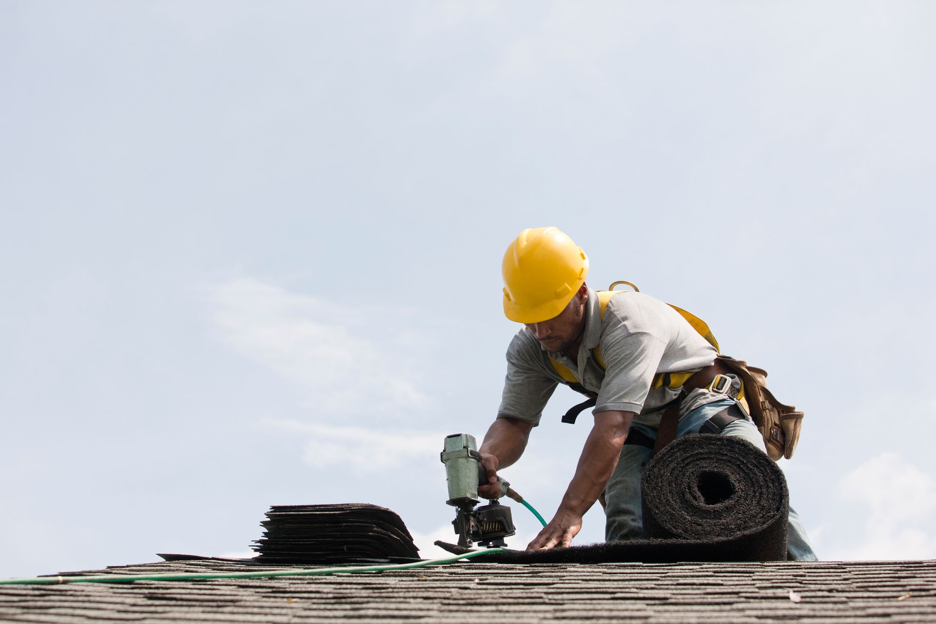 Roofer working on shingling a new roof for roofing installation by Thompson & Thompson 3rd Generatio