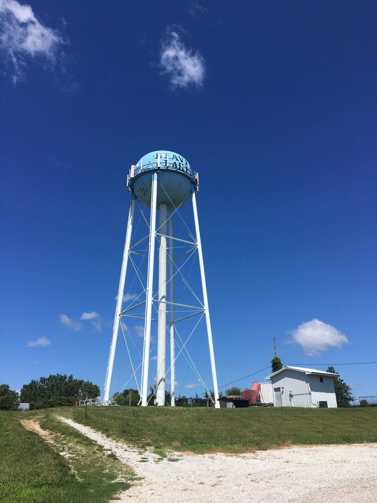 A water tower is sitting on top of a grassy hill.