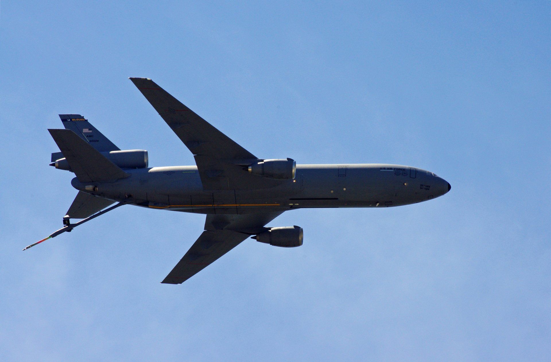 A large military plane is flying through a clear blue sky.