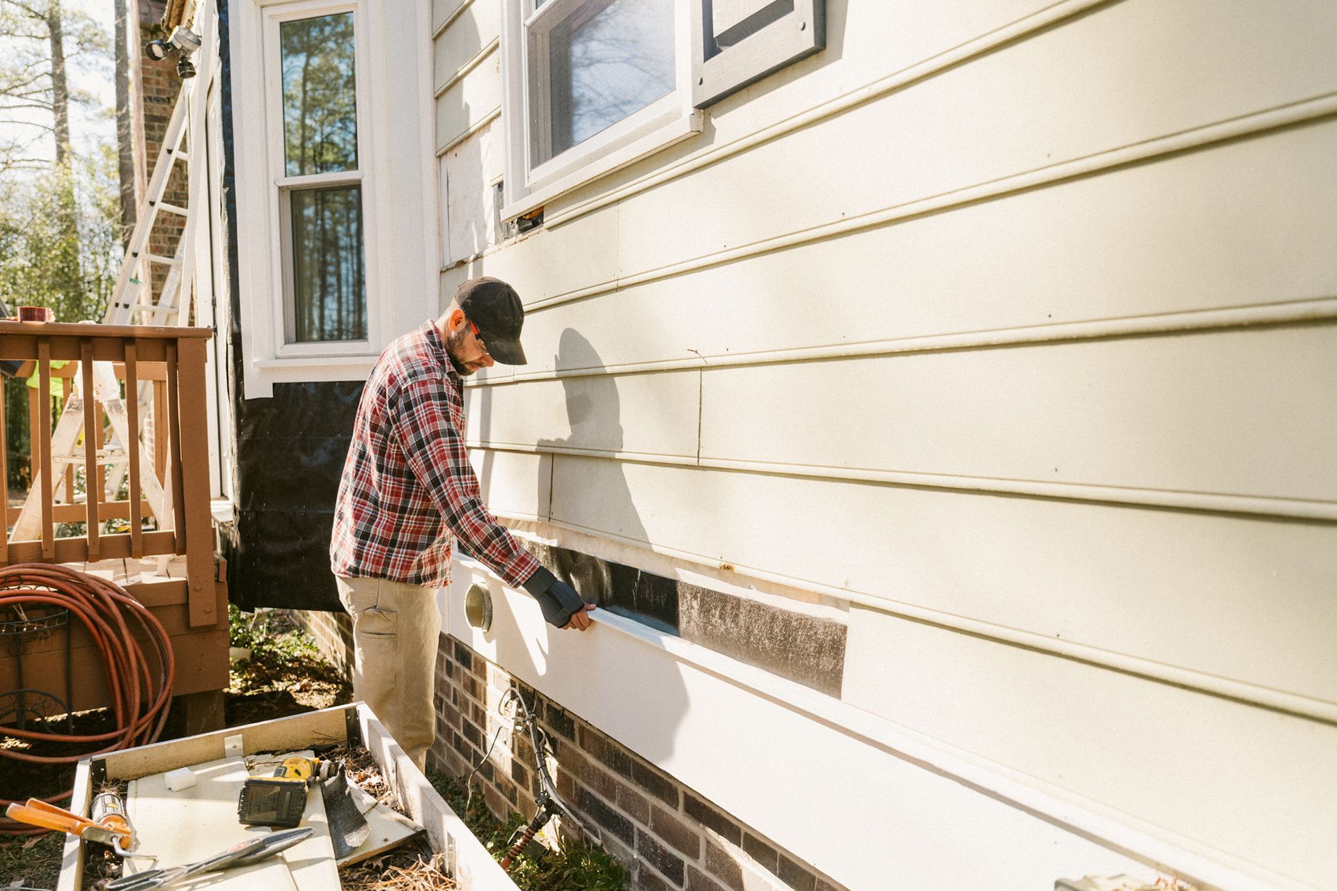 Construction worker repairing a colonial-style house, showcasing residential siding installation.