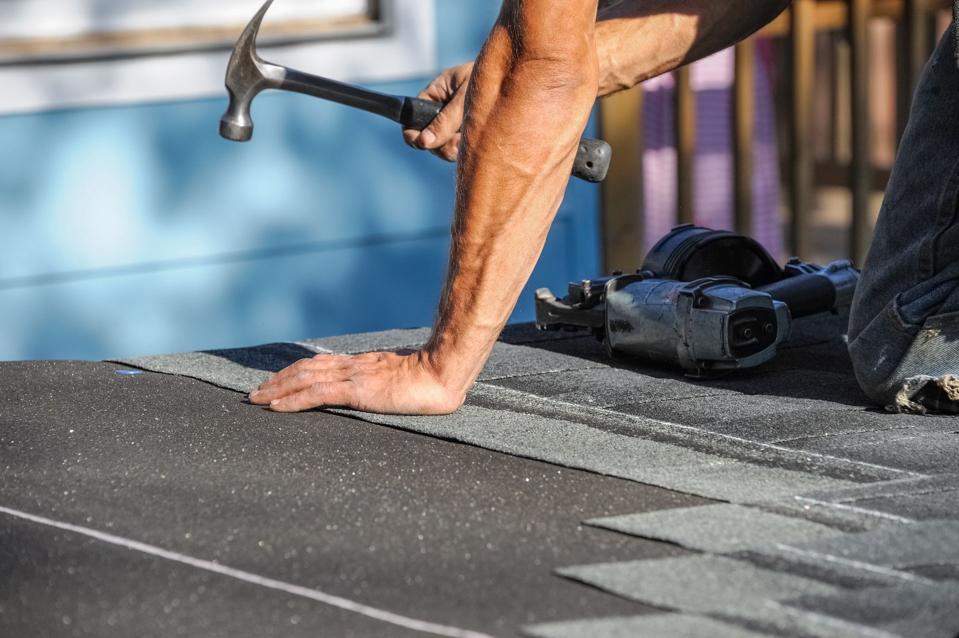 Close-up of a residential roof maintenance contractor using a hammer to repair a roof. Close-up of a residential roof maintenance contractor using a hammer to repair a roof.