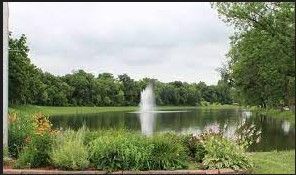 There is a fountain in the middle of a lake surrounded by trees.