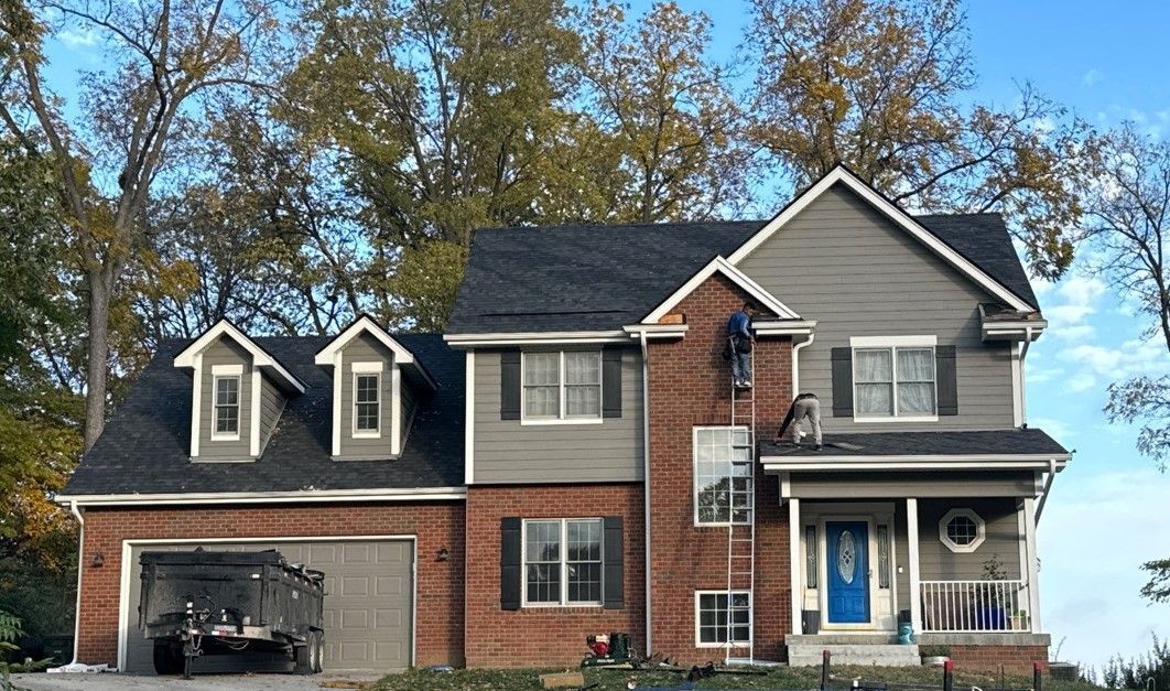 A large brick house with a black roof and a blue door