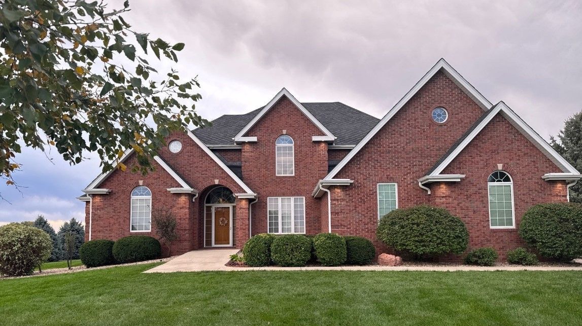 A large brick house with a lush green lawn in front of it
