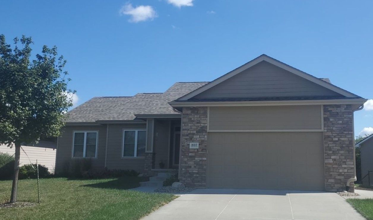A house with a large garage and a tree in front of it.