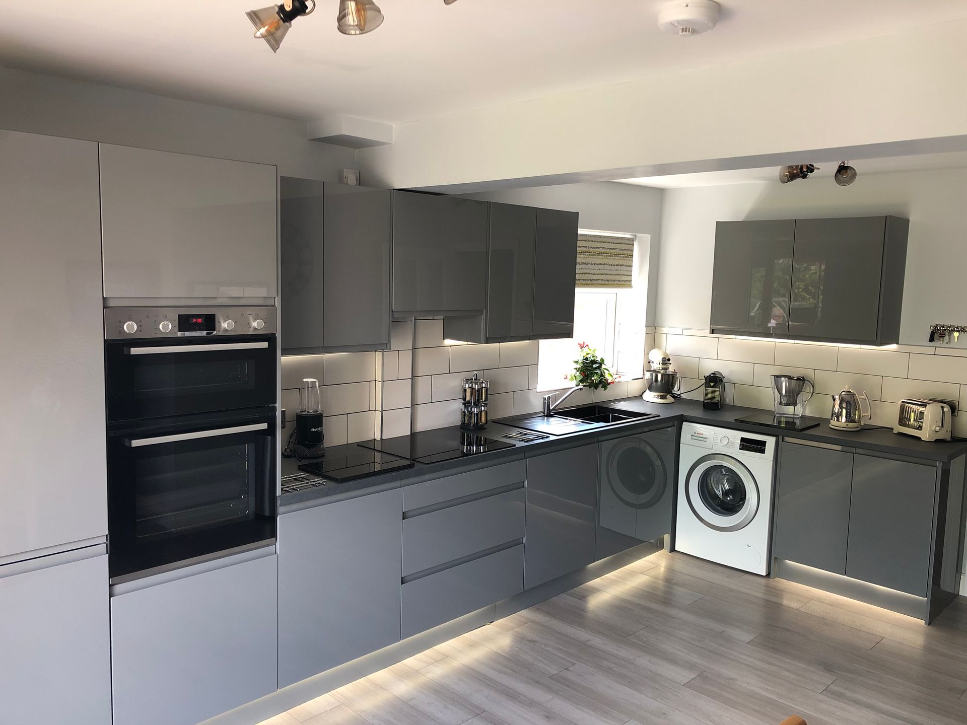 A kitchen with gray cabinets , a washer and dryer , and a stove.
