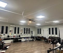 A spacious music studio with soundproofing panels, a drum set, and recording equipment.