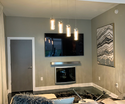 Living room with a mounted TV, fireplace, art, and hanging lights.