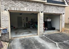 Two open garage bays with gray brick exterior. One is cluttered, the other is less so.