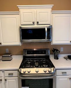 White kitchen cabinets with a microwave over a stainless steel gas stove.