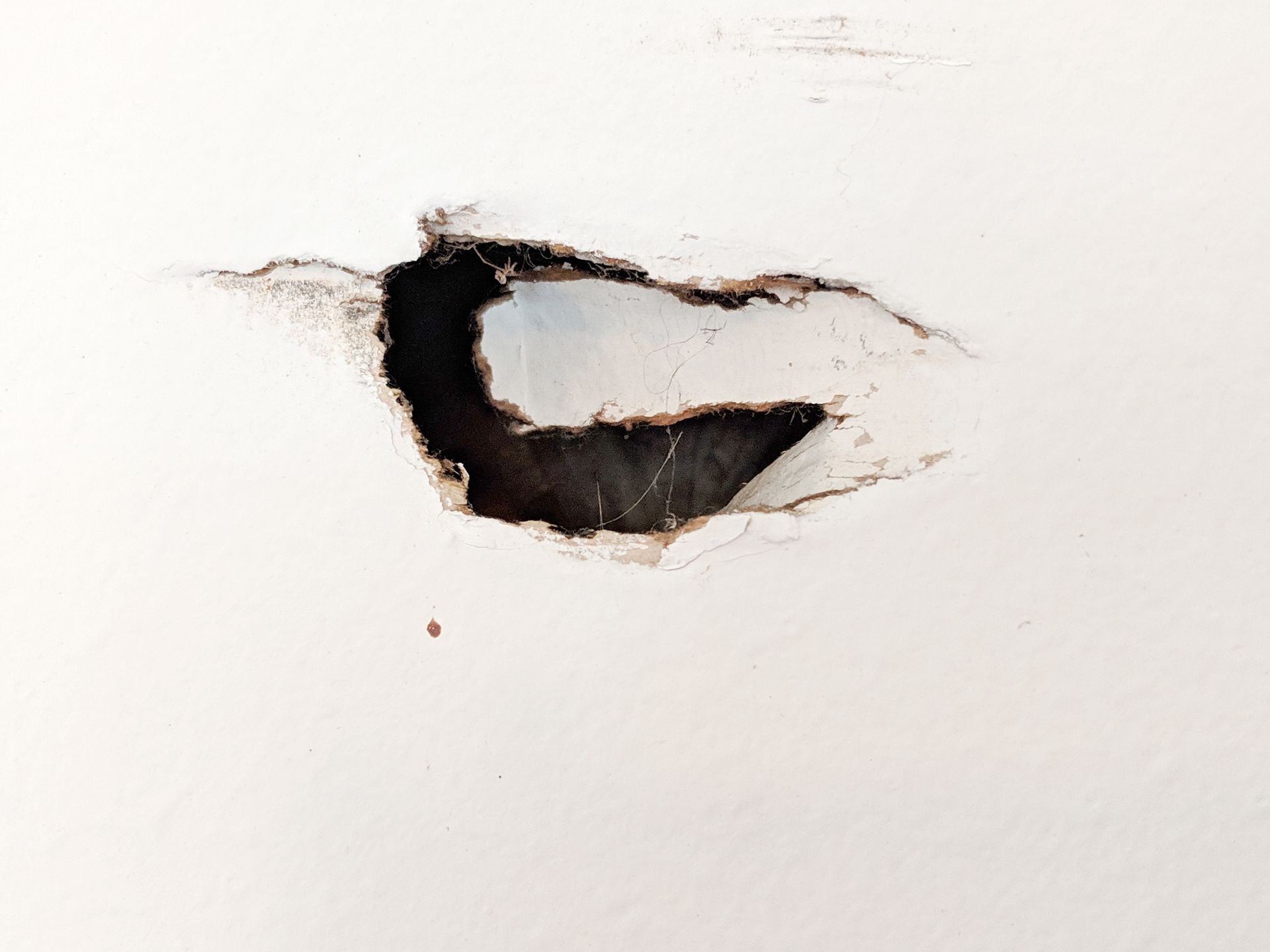 A hole in a white wall with a black hole in it.