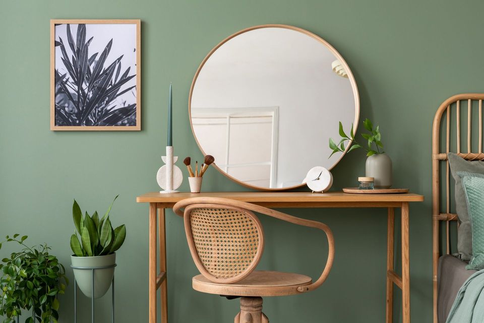 A vanity with a round mirror and a chair in a bedroom.