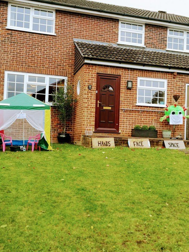 Brick house front with a green tent, a tree, and signs saying 