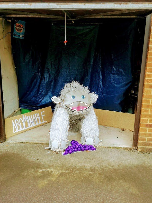 A yeti-like sculpture made of white materials stands in an open garage, with a sign reading 