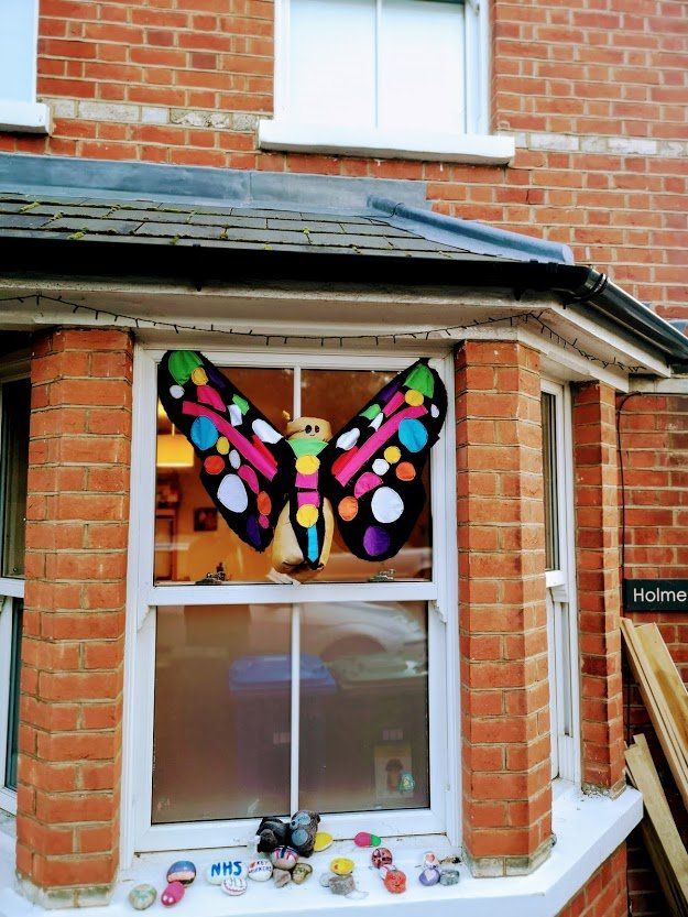 Colorful butterfly artwork in a window of a brick building.