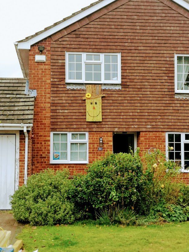 Brick house with a yellow smiley face decoration hanging from the second-story window.