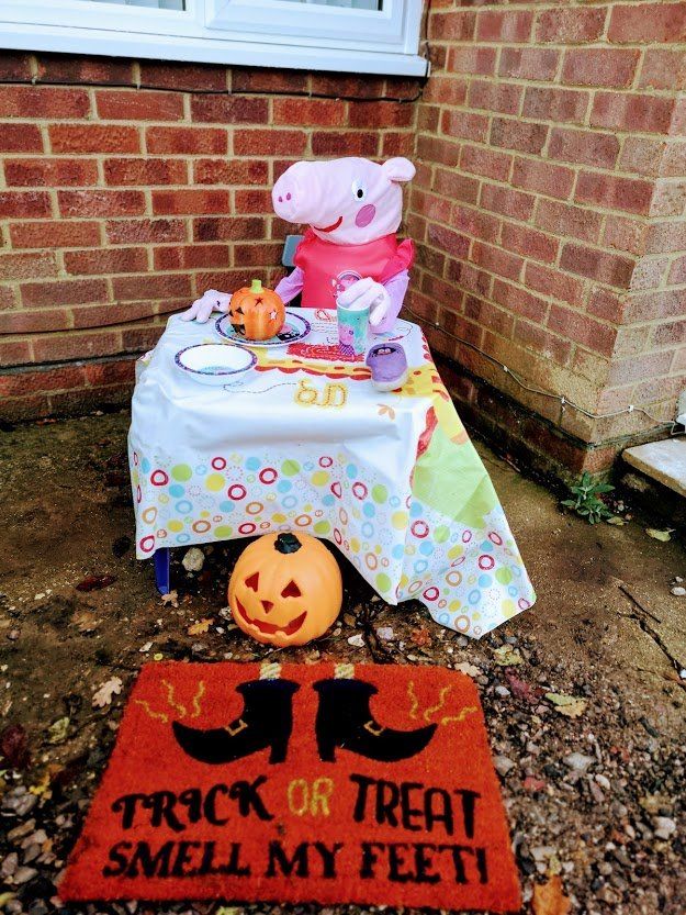 Peppa Pig scarecrow at a table with Halloween treats, jack-o'-lantern, 