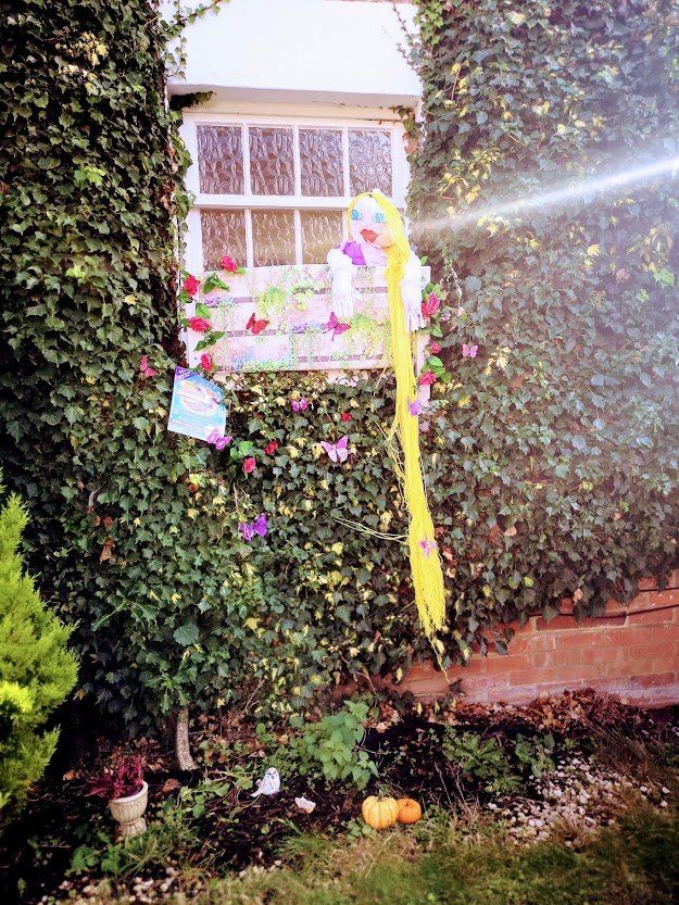 Window decorated like Rapunzel's tower, covered in ivy. A long yellow braid hangs from the window.