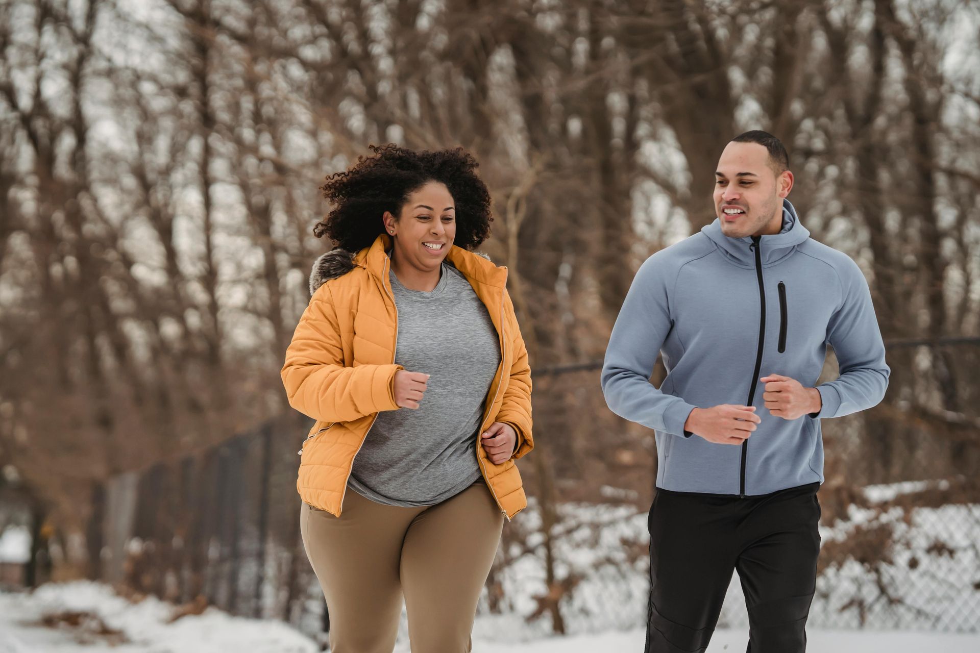 A man and a woman are jogging in the snow to build healthy weight loss habits.