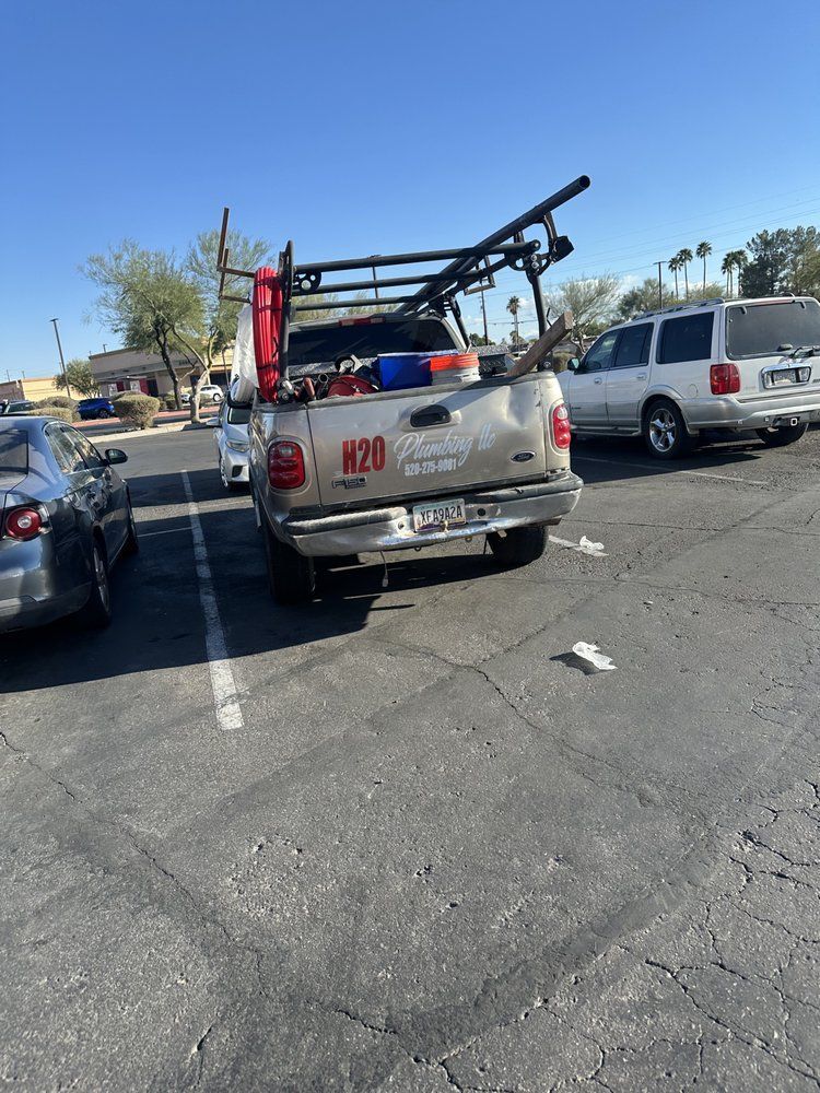A silver work truck with a ladder rack parked in a parking lot on a sunny day.