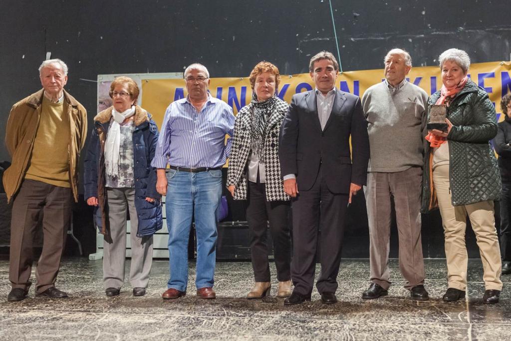Un grupo de personas en el escenario, algunas sonriendo. Una pancarta dice