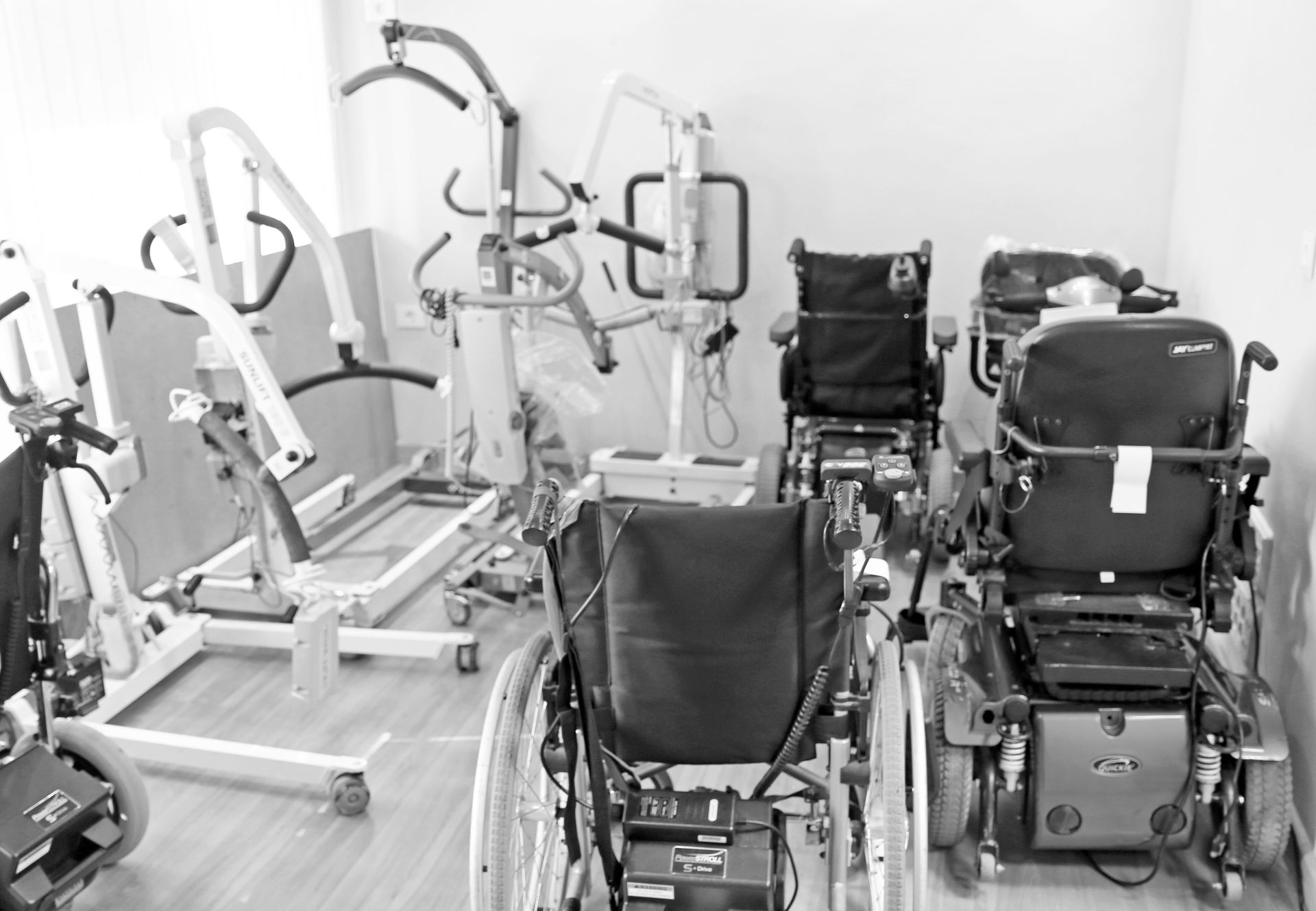 Sillas de ruedas y elevadores de pacientes en una sala de almacenamiento de equipos sanitarios.