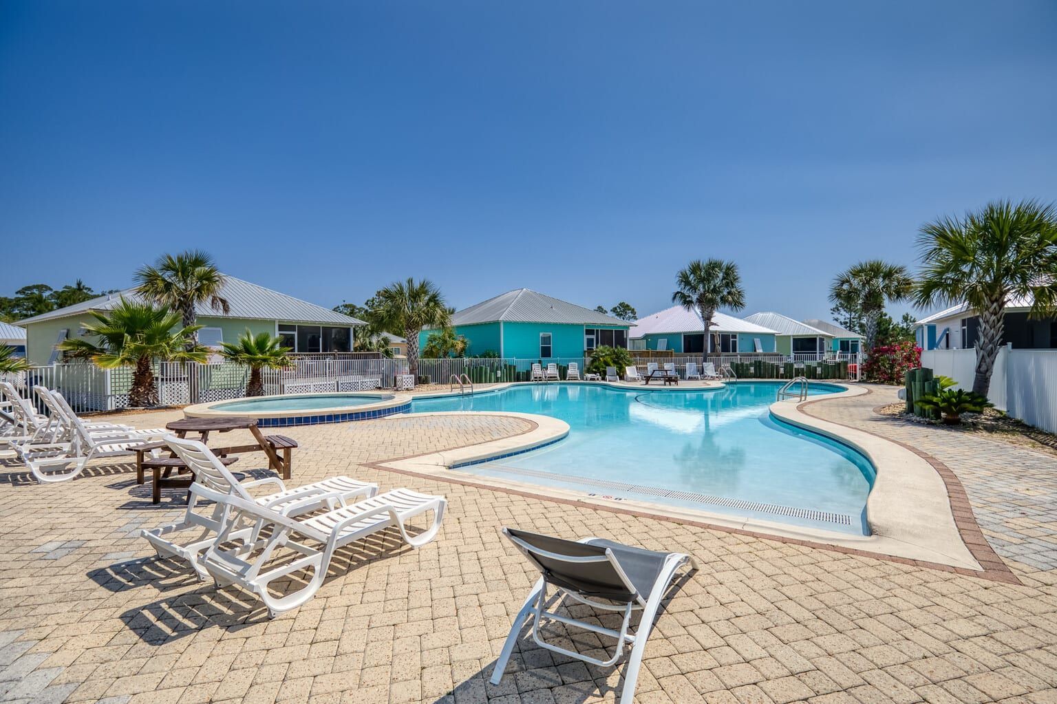 A large swimming pool surrounded by chairs and palm trees in a resort.