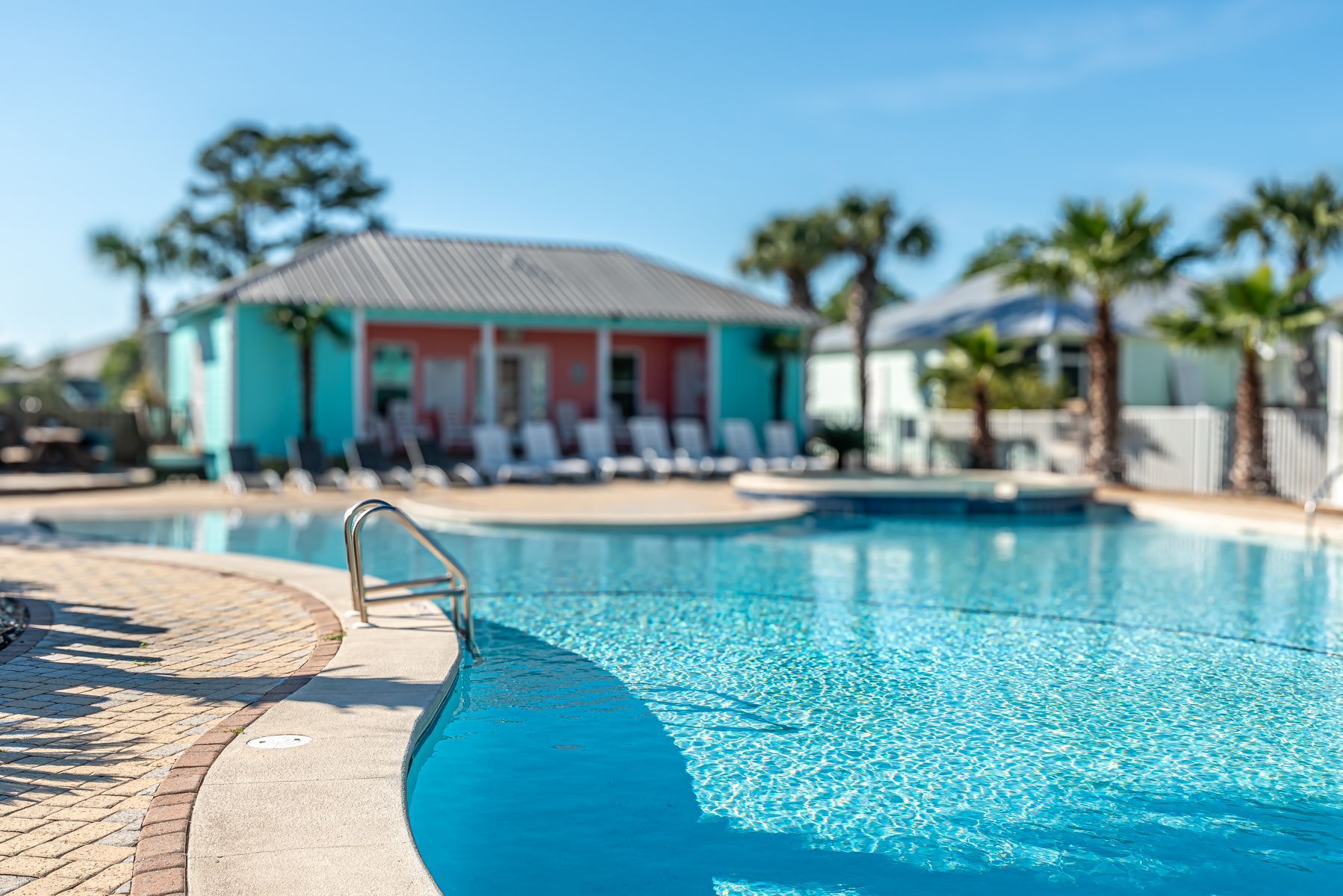 A row of white lounge chairs sitting next to a large swimming pool.