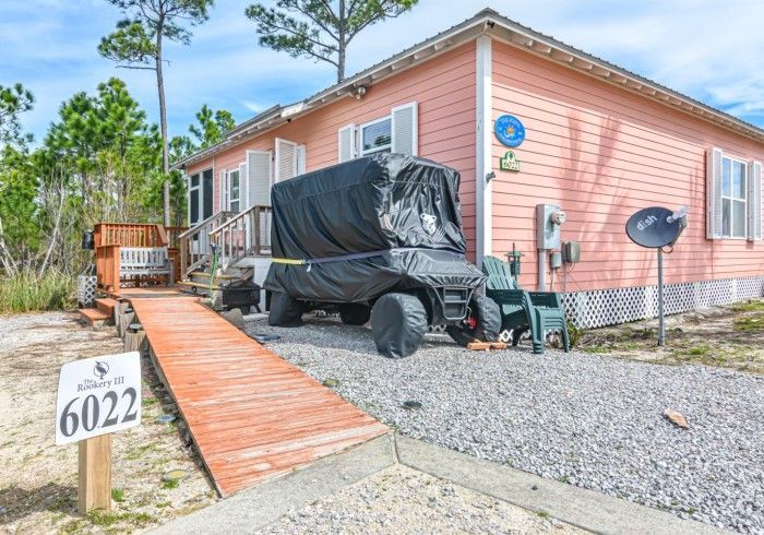 A golf cart is parked in front of a pink house.