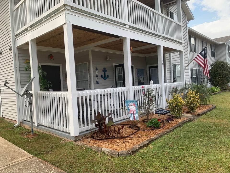 A white house with a porch and a flag on it.