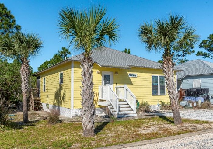 A yellow house with palm trees in front of it