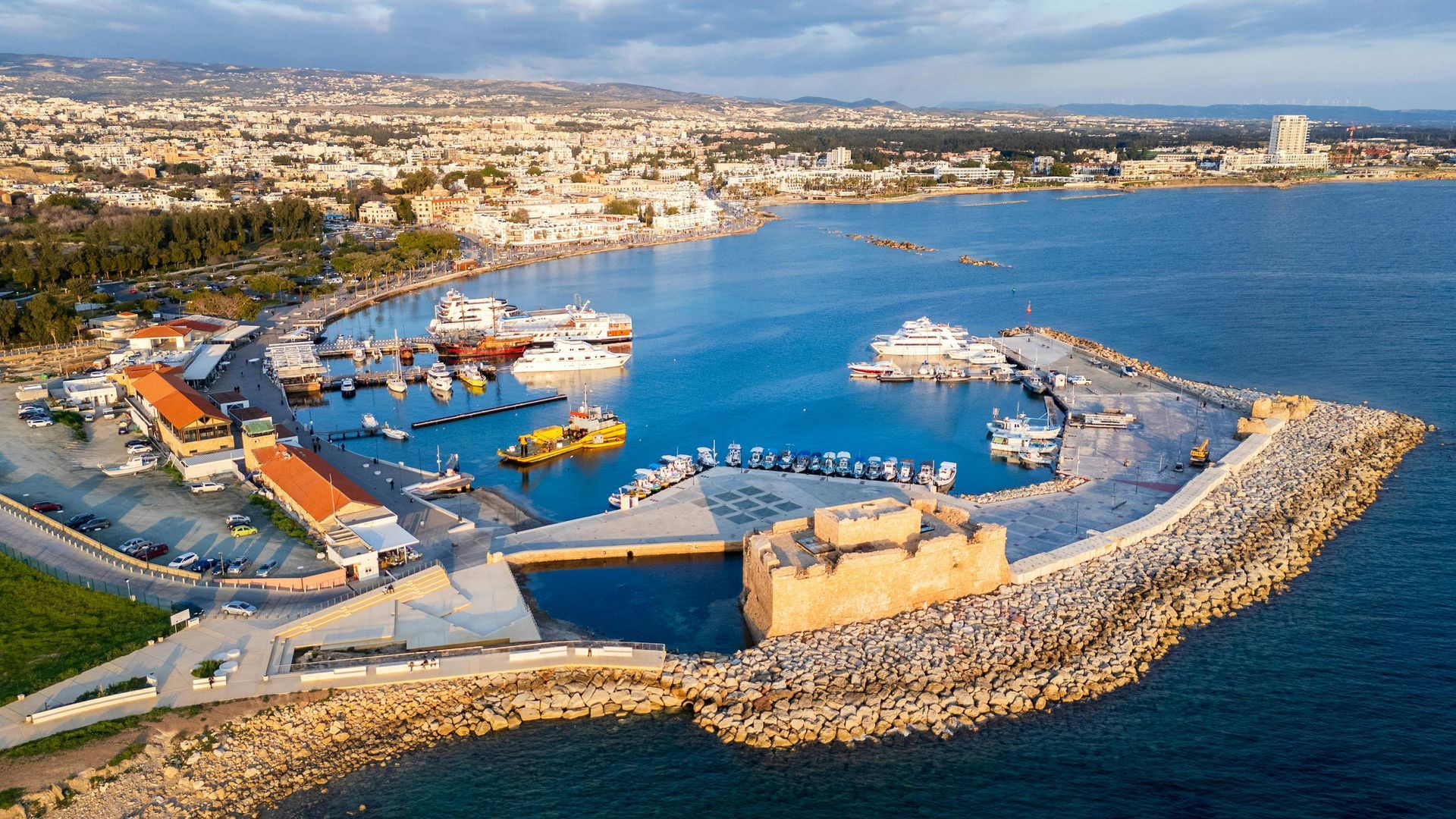 An aerial view of a harbor with boats in it and a city in the background.