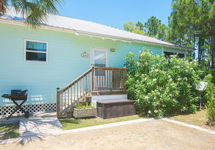 A small blue house with a wooden deck and stairs.