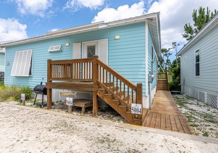 A blue house with a wooden deck and stairs
