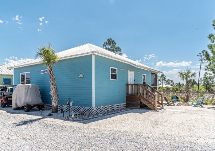 A blue house with a golf cart parked in front of it.