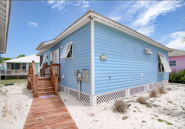 A blue house with a wooden walkway leading to it