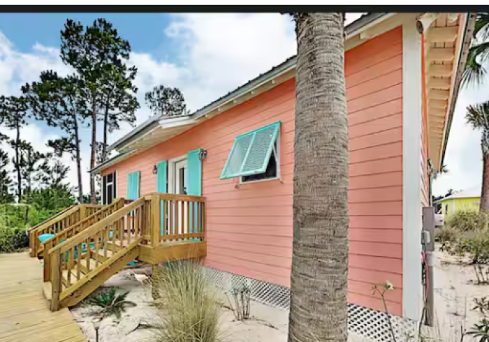 A pink house with blue windows and a wooden deck