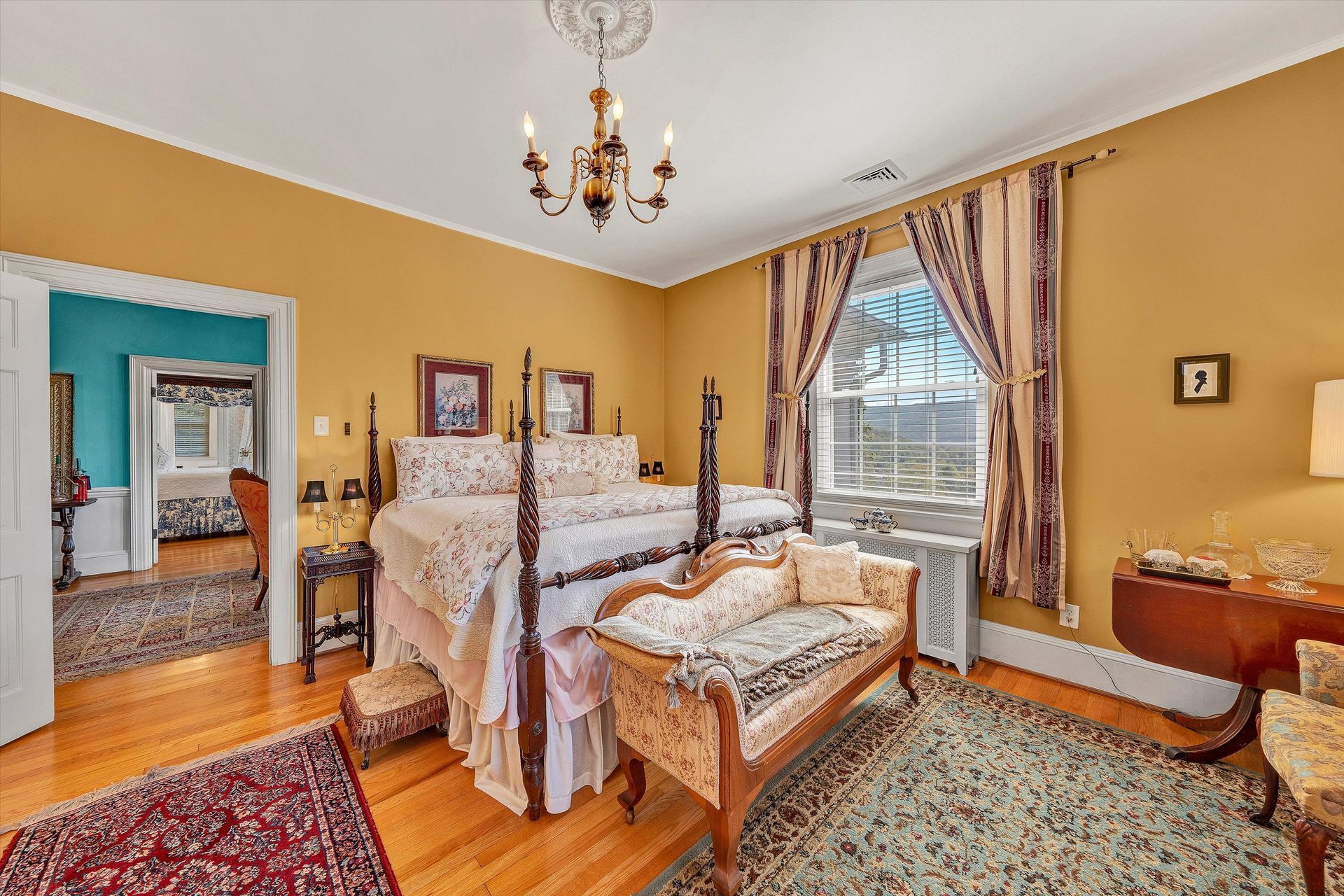 Vintage bedroom with yellow walls, canopy bed, bay window, and ornate decor