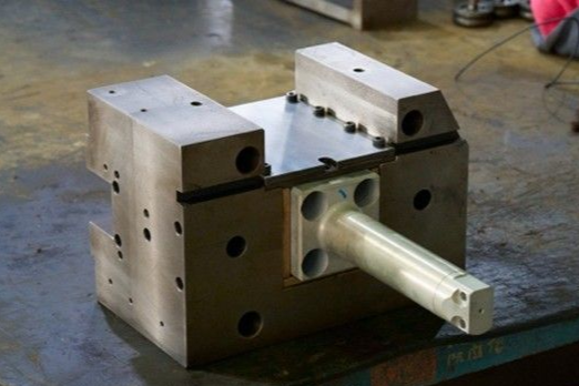 Machined metal block with a silver rod extending from the front.