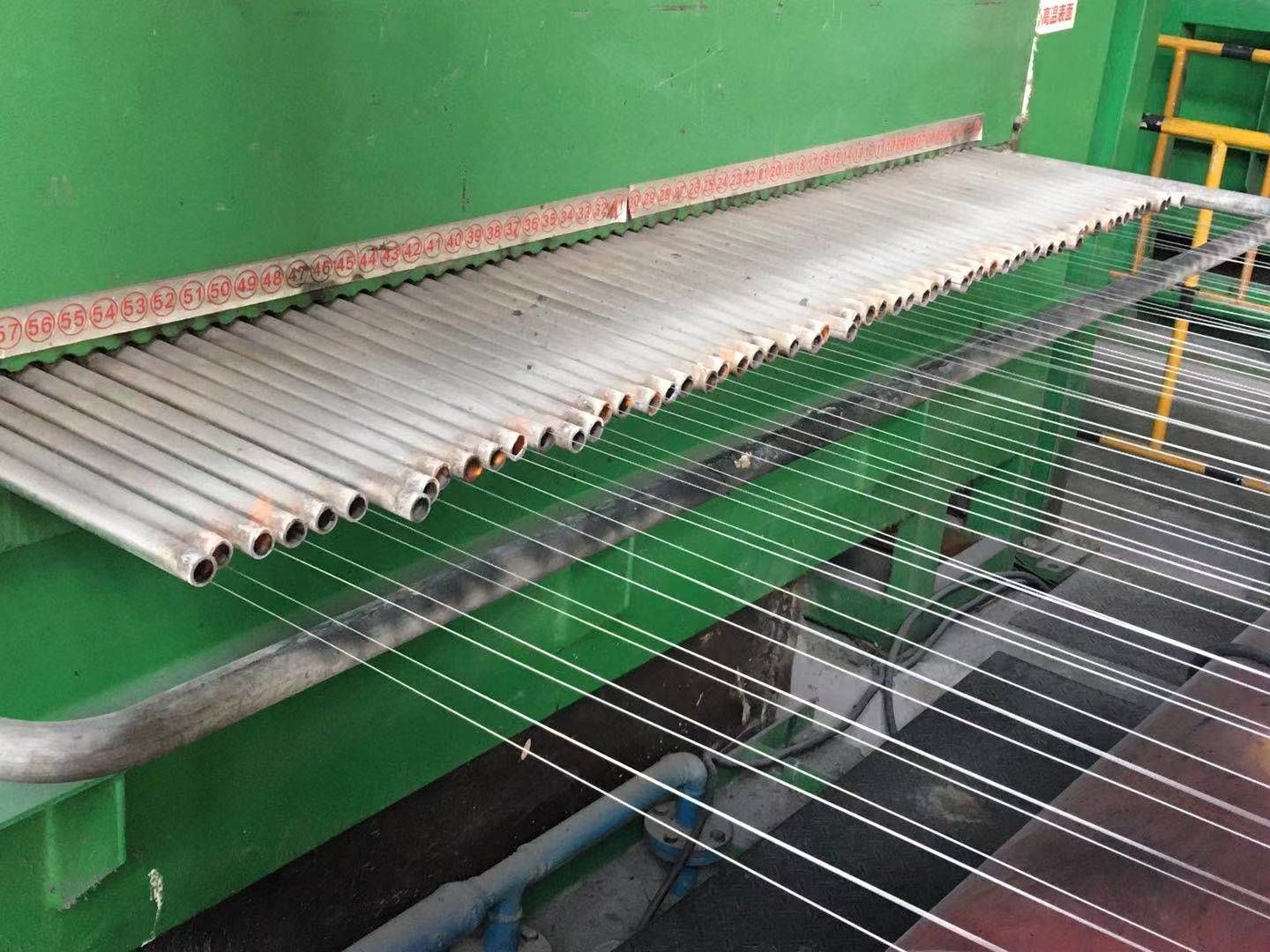 Metal tubes with strings extending below, likely part of a textile manufacturing process.