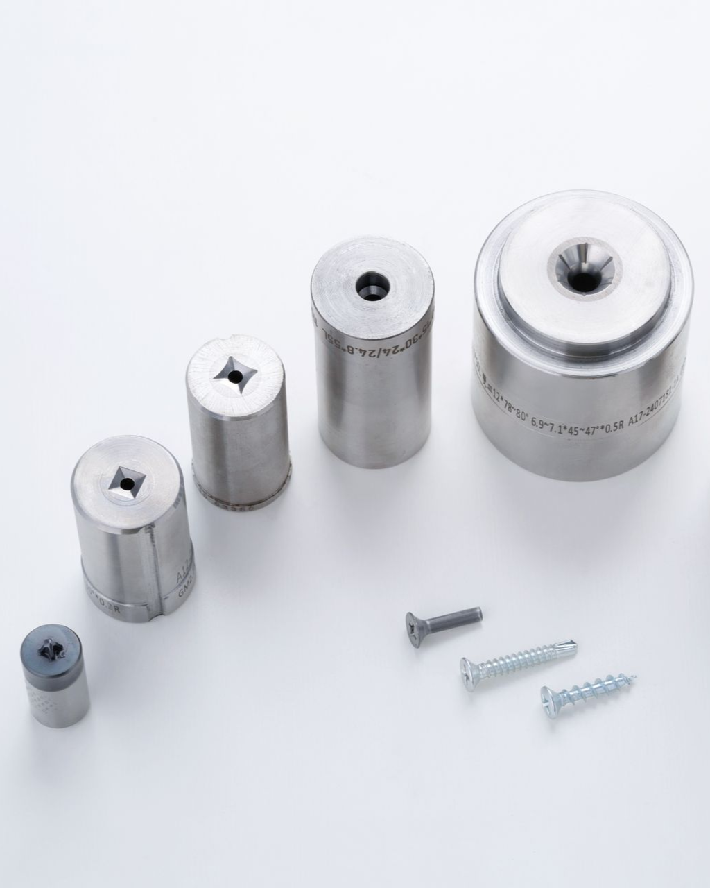 Five metal dies of varying sizes with screws against a white background.