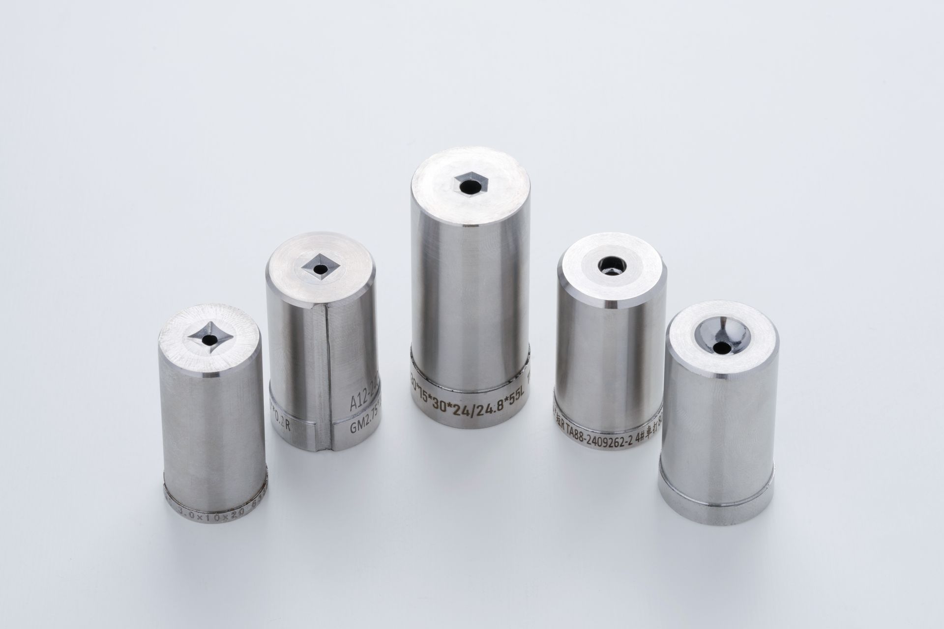 Five shiny metal punch tools, each with a different shaped hole.