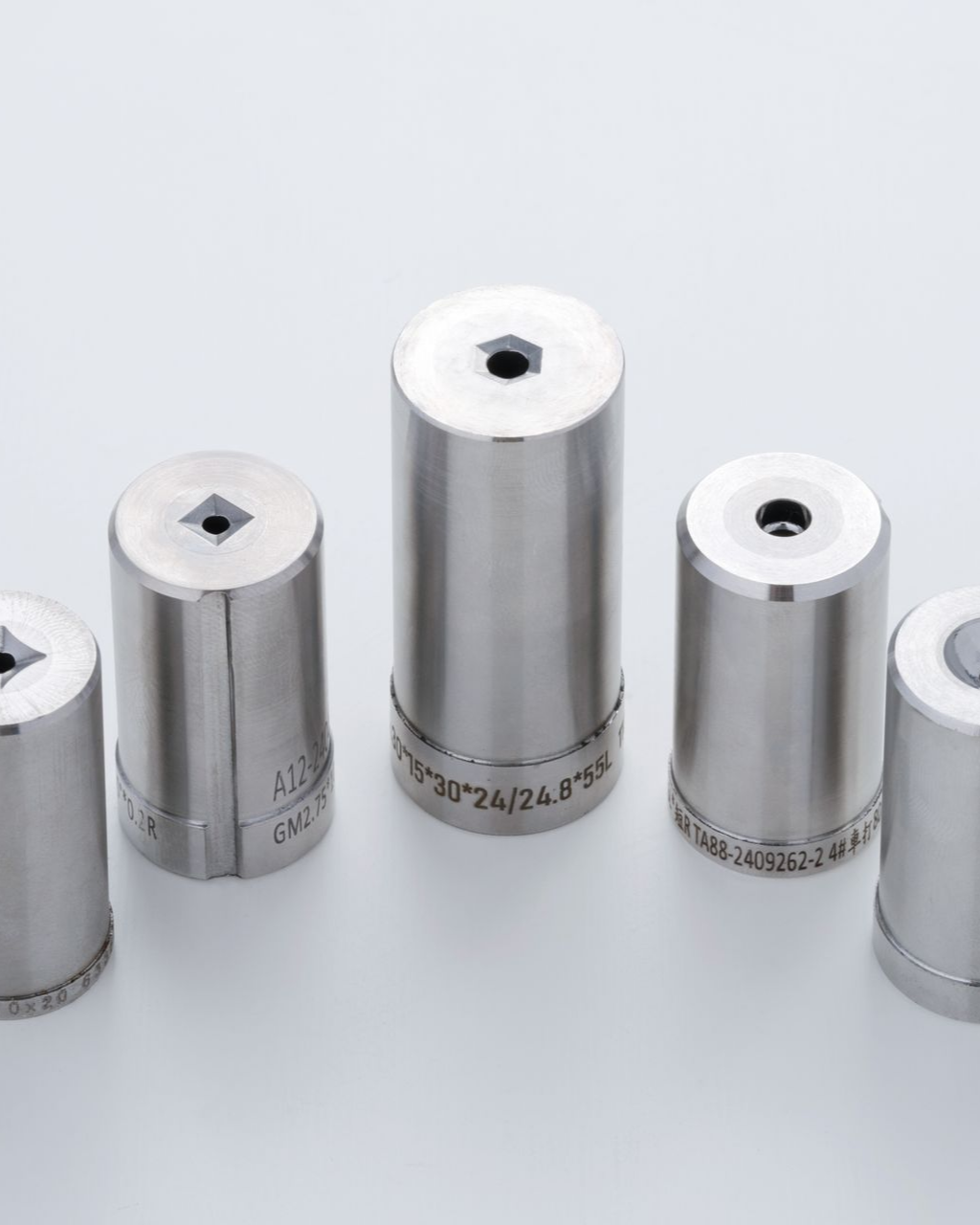 Five shiny metal punches with different shaped holes.