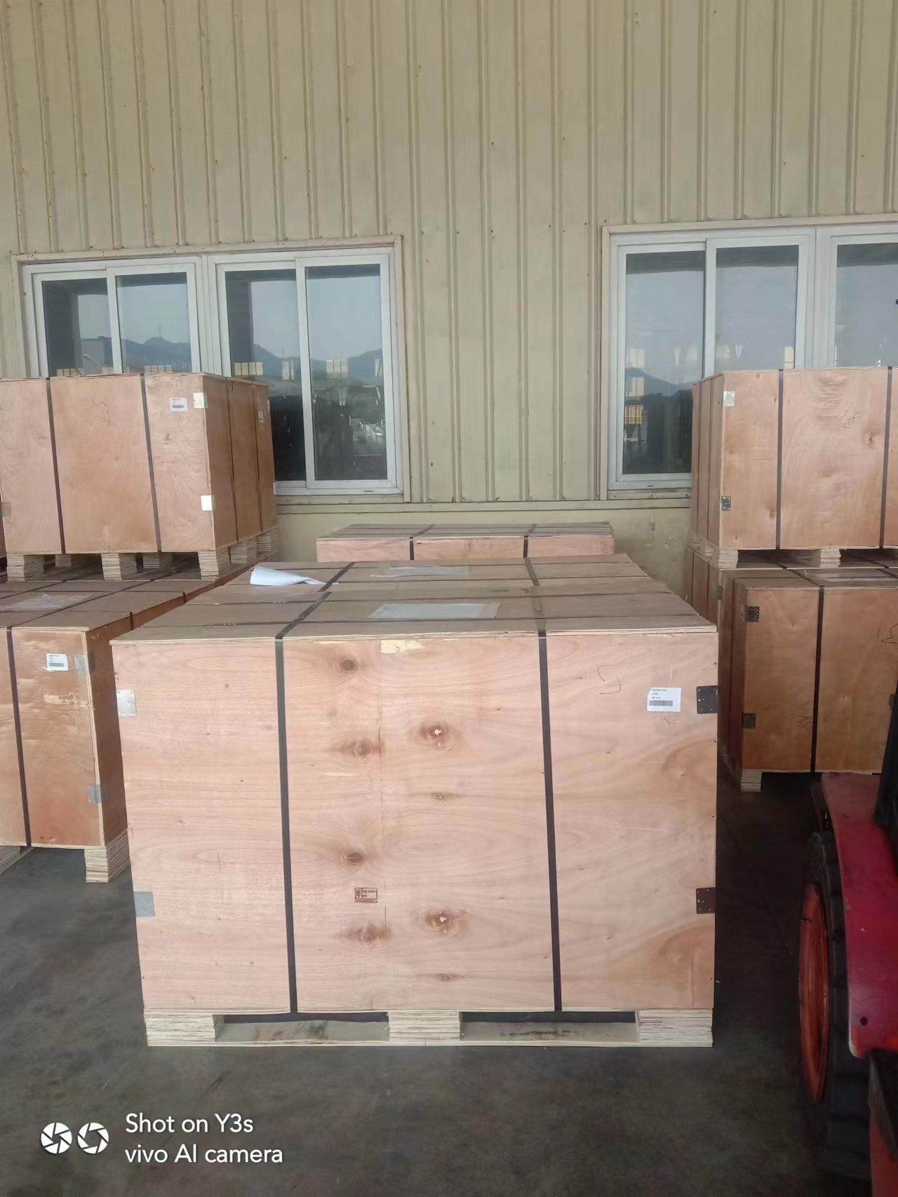 Wooden crates on pallets stacked in front of a building with windows; likely for shipping.